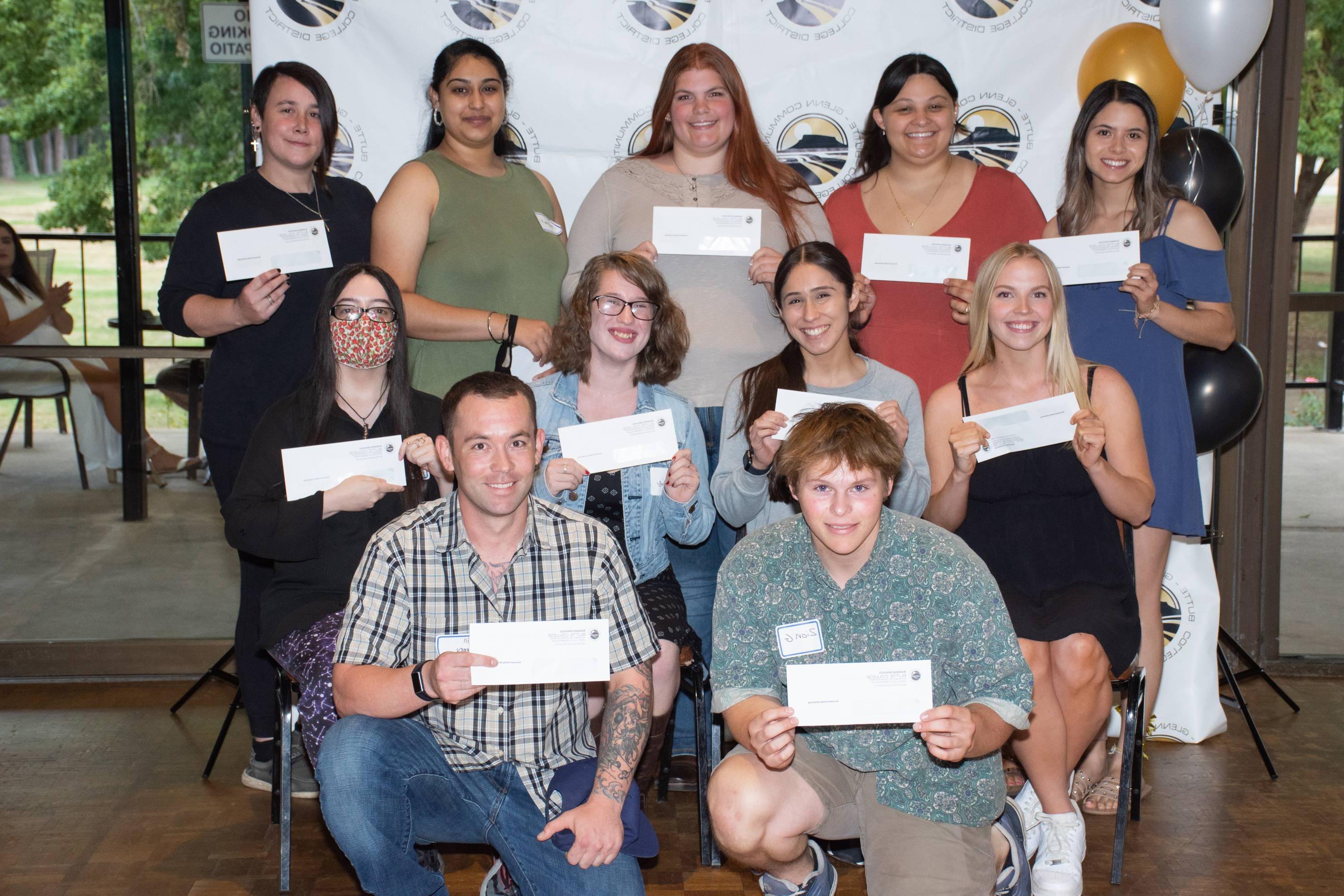 A group of students pose together while holding scholarship checks.